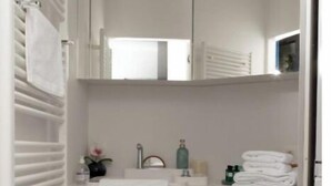 A compact, modern bathroom with a built-in sink, a mirror, and a towel rack. - Suite aux Anges N°1 (Antwerpen)
