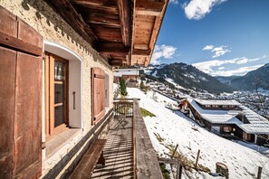 A wooden balcony with a view of a snow-covered village and mountains. - Chalet 'La Ferme De La Vora' with Mountain View, Private Terrace and Wi-Fi (CHATEL)