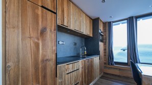 A modern kitchen with wooden cabinetry, a black countertop, and a window with curtains. - Apartment “Lesetoilesdelaplagne - Le Diamant” with Mountain View and Private Terrace (aime la plagne)