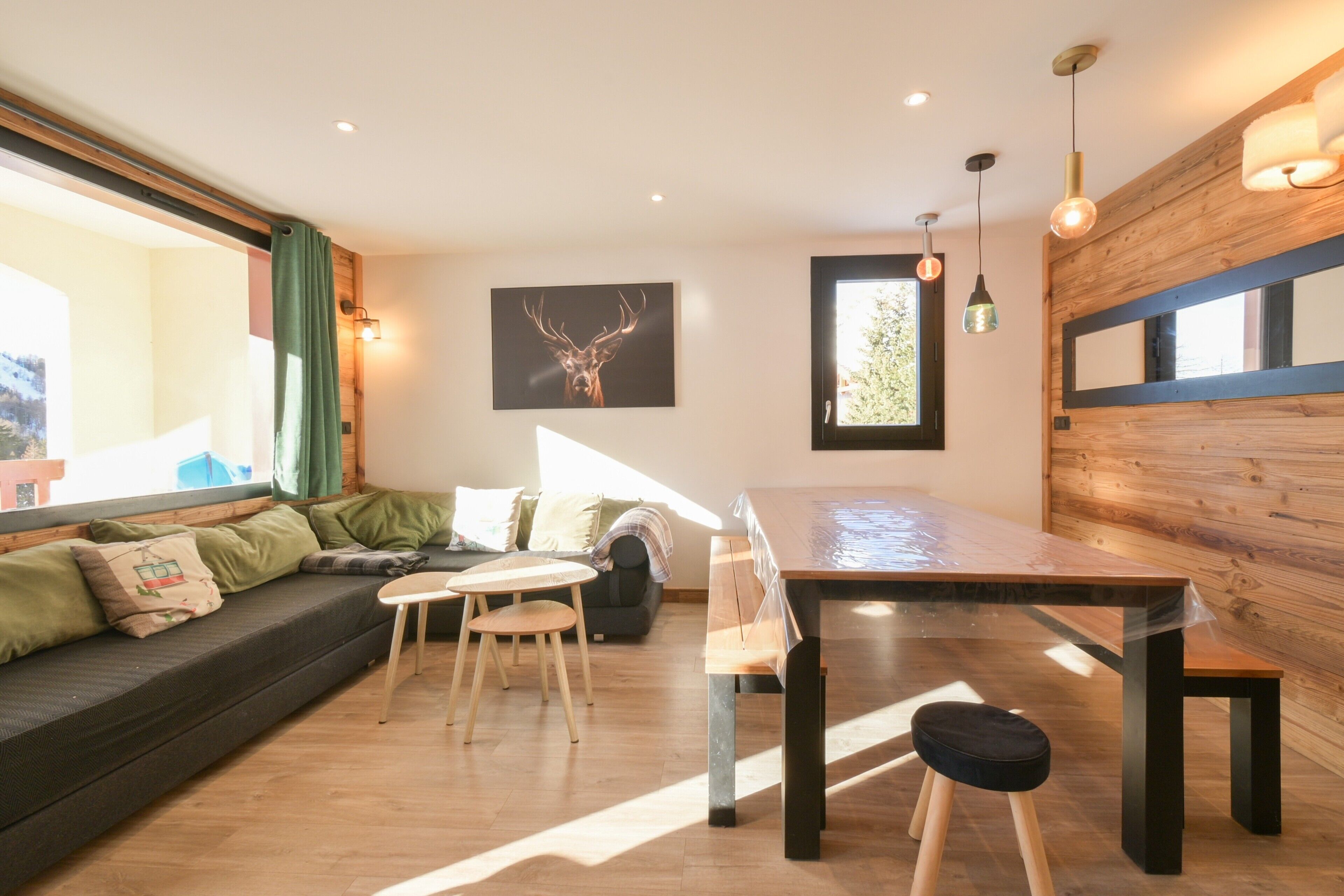 A modern living space with a sofa, dining table, chairs, and a large window.