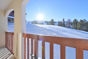 Un balcon doté d’une balustrade en bois, donnant sur un paysage enneigé et un ciel bleu dégagé.