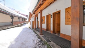 A snow-covered building with wooden doors and a covered walkway. - Spacious Chalet-Style Triplex Apartment for 10 in Belle Plagne, Ski-In/Ski-Out (La Plagne Tarentaise)