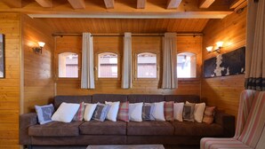 A wooden cabin interior with a brown sofa, a striped armchair, and a wooden coffee table. - Spacious Chalet-Style Triplex Apartment for 10 in Belle Plagne, Ski-In/Ski-Out (La Plagne Tarentaise)
