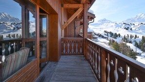 A wooden balcony with a view of snow-covered mountains.