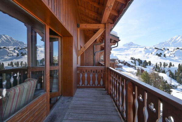 A wooden balcony with a view of snow-covered mountains.