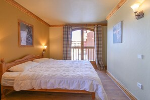 Ein Schlafzimmer mit einem hölzernen Bett, einem Balkon mit Vorhängen und einem Gemälde an der Wand.
