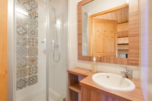 Ein Badezimmer mit Dusche, Waschbecken, Spiegel und Holzschrank.