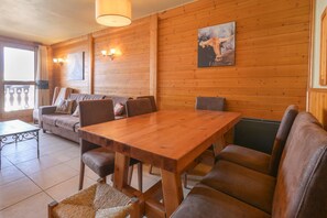 Ein Holzinnenraum mit einem Esstisch, Sofas und Blick ins Freie.