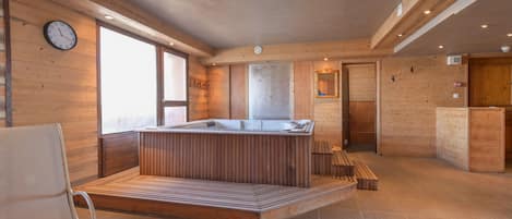 A modern interior with a wooden reception desk, a seating area, and a large window.