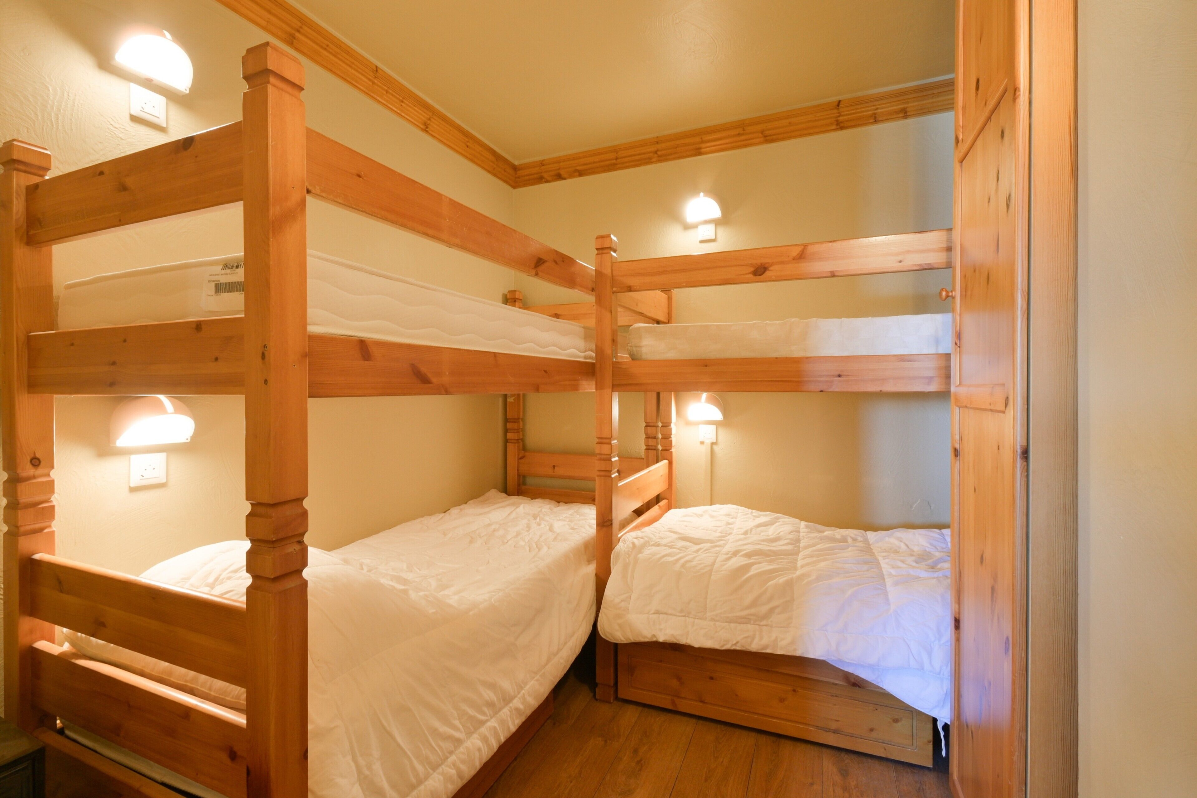 A bunk bed room with wooden frames and white bedding.