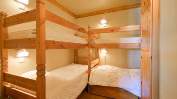 A bunk bed room with wooden frames and white bedding.