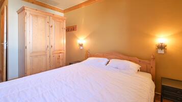 A bedroom with a wooden bed, two wall-mounted lights, and a wardrobe.