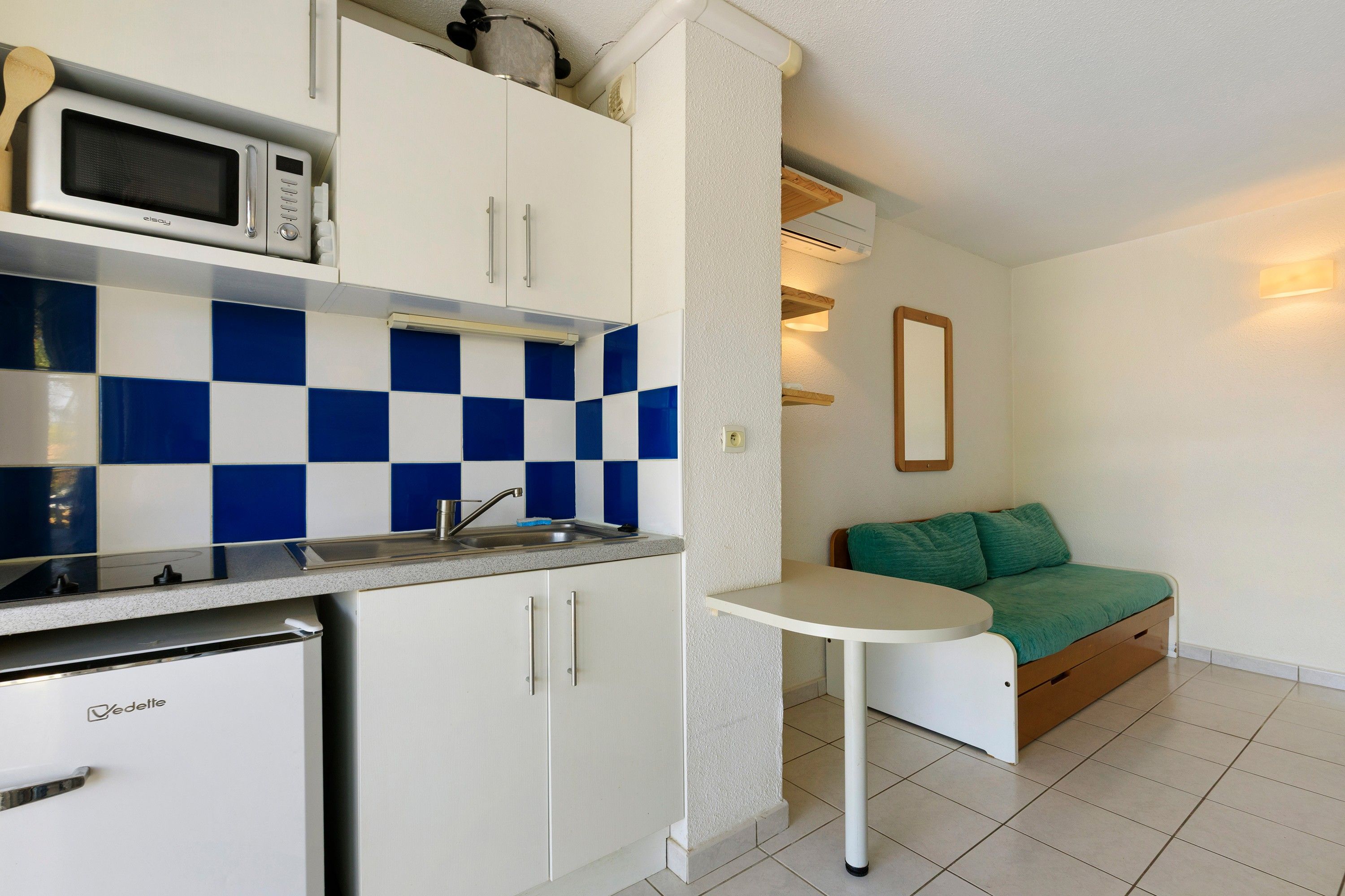 A compact kitchenette with a microwave, sink, and storage cabinets.