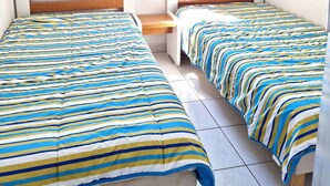 A room with two beds, a window, a bedside table, and a lamp. - Apartment 'Cap d'Agde - Primavera - 2' with Sea View, Shared Pool and Air Conditioning (Agde)