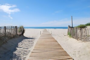 En träpromenad som leder till en strand med en klar himmel.