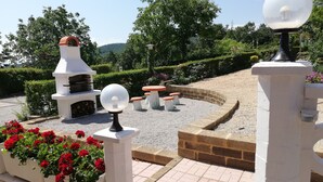 A garden area with a barbecue grill, outdoor seating, and decorative lighting. - Between S. Gimignano and Volterra in the peace of the woods of Tuscany (Gambassi Terme)