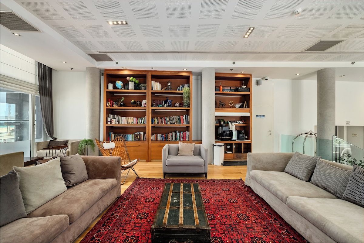 Un salon moderne avec deux canapés, une table basse et une grande bibliothèque remplie de livres et d’objets décoratifs.