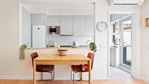 A compact kitchen with white cabinets, a microwave, and a clock on the wall. - GuestReady - Santa Catarina Skyflat (Porto)