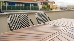 A wooden table and two wicker chairs on a rooftop terrace. - GuestReady - Santa Catarina Skyflat (Porto)