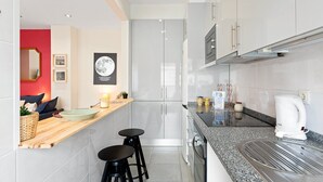 A modern kitchen with a built-in oven, a coffee machine, and a small bar area with stools. - GuestReady - Santa Catarina Skyflat (Porto)