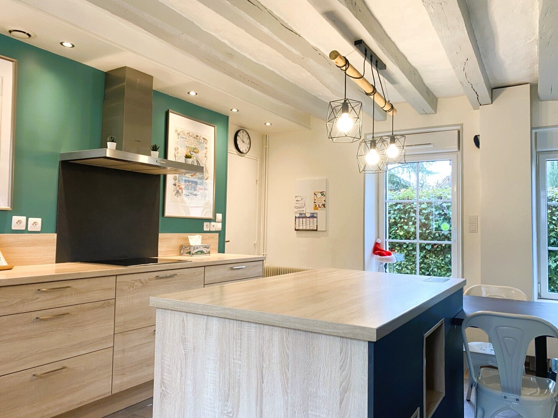 Une cuisine moderne dotée d’un îlot central, de meubles en bois, d’une cuisinière encastrée et de luminaires suspendus.