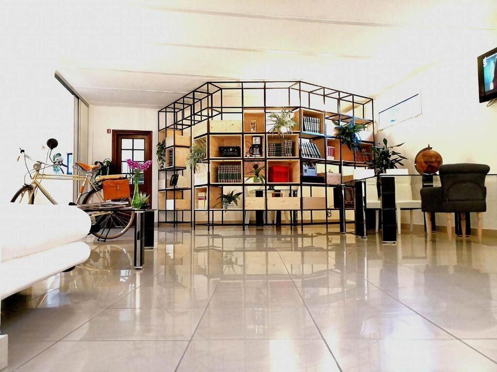 Una sala de estar moderna con una estantería geométrica central, un sofá blanco, una bicicleta y una mesa de centro de vidrio.