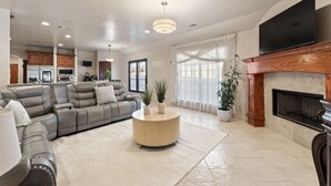 A modern living room with a grey sectional sofa, a round coffee table, and a fireplace. - Luxury Pool Home w/ Outdoor Lounge Near Stadium (Irving)
