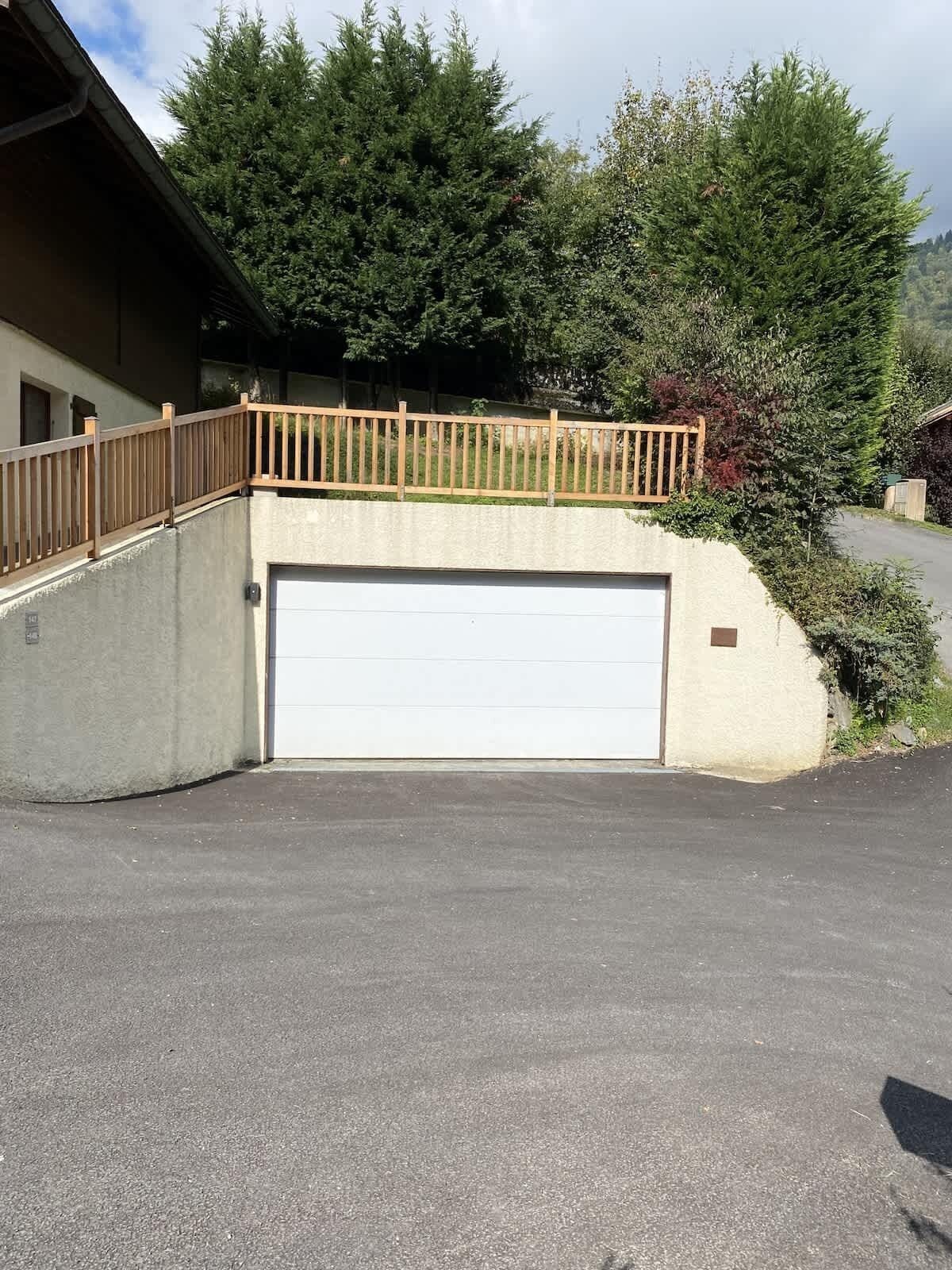 Een gebouw met een garagepoort, een houten omheining en een verharde oprit.