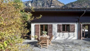 Un chalet con un patio de piedra, muebles de madera y vistas a la montaña.