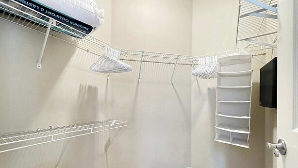 A corner closet with white wire shelves, a hanging rack, and a shoe rack. - Peaceful 2 BR with Private Garage, Prime North Tampa (Lutz)