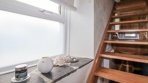 A room with a window, a white vase, a small bowl with seashells, and a wooden ladder. - Trevrock (Penzance)