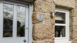A stone house with a white door and a window with a small shelf. - Trevrock (Penzance)