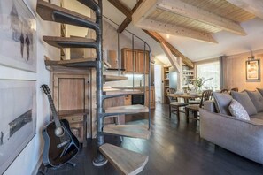 Amplia sala de estar con una escalera que lleva a un nivel superior, un comedor y una zona de estar acogedora con un sofá.