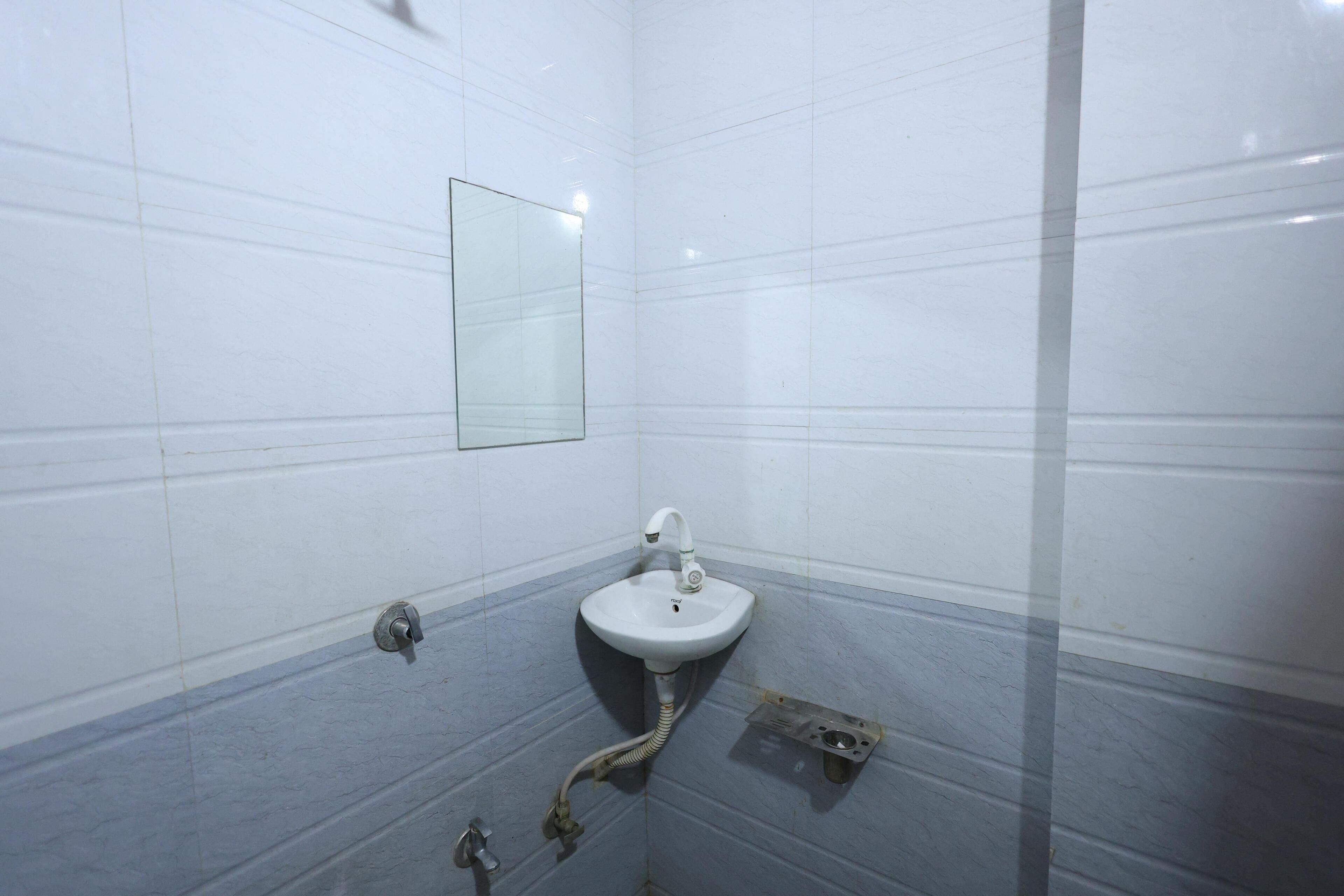 Un baño con lavamanos blanco, un espejo y desagüe de ducha.