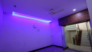 A room with a ceiling fan, a staircase, and a purple underglow lighting. - Hotel Royal Raj (Rajkot)