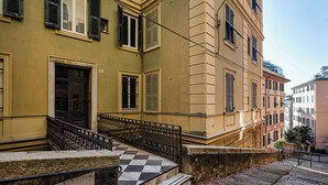 A building with a checkered floor, a black wrought iron staircase, and a door with a decorative metal grille. - The Designer's Flat by Wonderful Italy (Genoa)