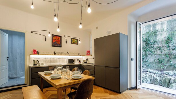 A modern kitchen with a dining table set for four, a refrigerator, and a large window with a view of greenery. - The Designer's Flat by Wonderful Italy (Genoa)
