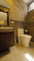 Un baño moderno con inodoro, bidé y espejo sobre el lavamanos.