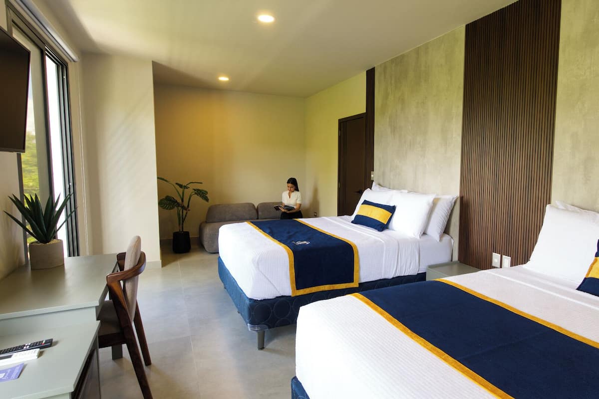 A hotel room with two beds, a desk, and a chair.