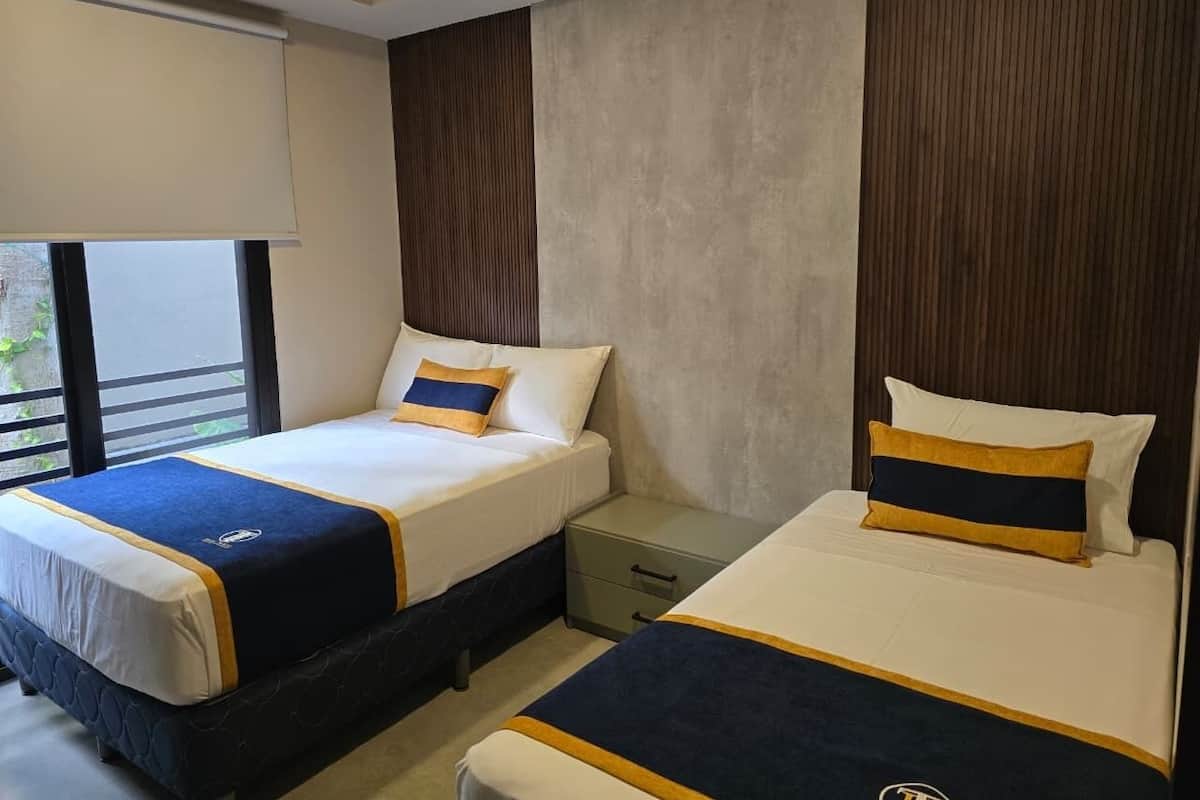 A hotel room with two beds, a nightstand, and a window with a view.