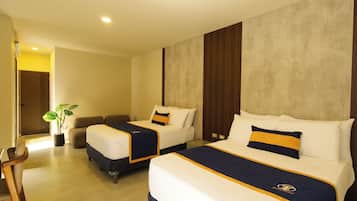 Quarto de hotel com duas camas, um espaço para sentar e um vaso de planta.