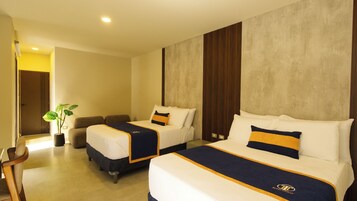 Quarto de hotel com duas camas, um espaço para sentar e um vaso de planta.