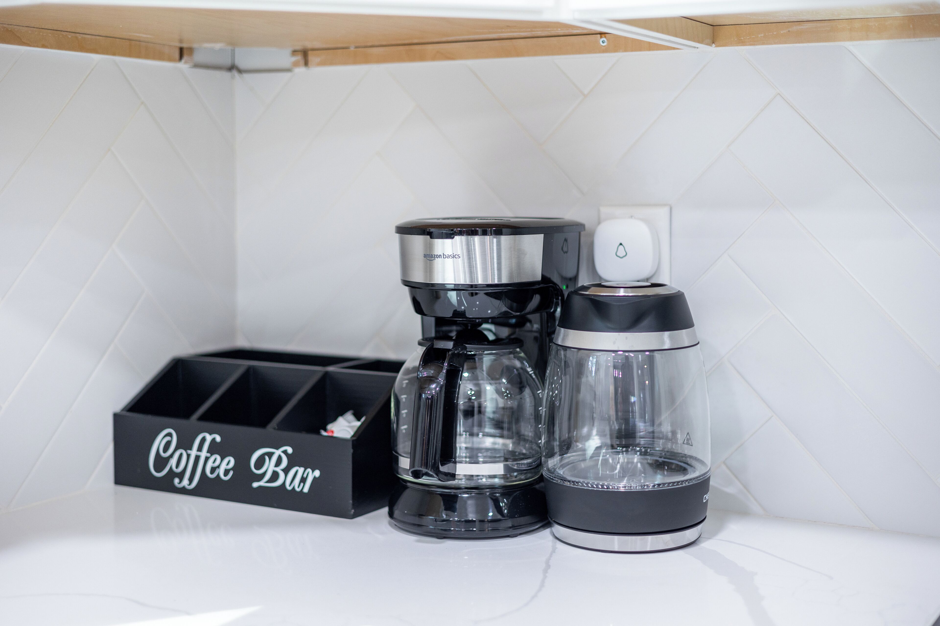 A coffee maker and a water dispenser on a white countertop with a 'Coffee Bar' sign.
