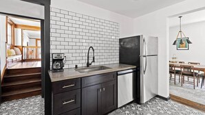 Una cocina moderna con refrigerador negro, pileta de acero inoxidable y muebles oscuros.