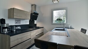 Cozinha moderna com bancada de madeira, fogão embutido e janela que oferece iluminação natural.