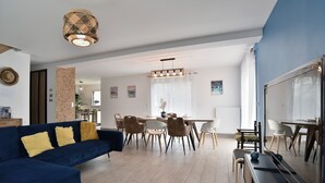 Uma sala de estar moderna com um sofá azul, área de jantar com cadeiras e um espelho grande.