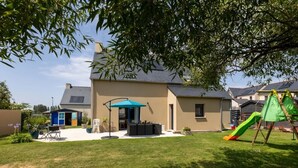 Uma casa com alpendre, área de recreação e gramado.