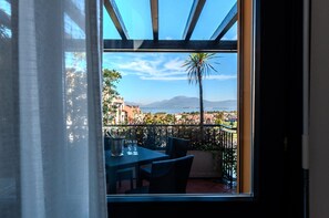 Un balcon avec une table et des chaises, une vue sur le paysage urbain et une montagne à l’horizon.