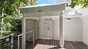 A covered outdoor area with a wooden deck, a metal railing, and a door marked with the number 424.