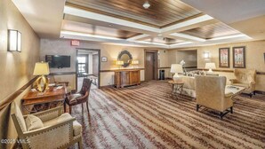 Un'hall d'albergo con un'ampia zona tappezzata, una televisione, una reception e zone salotto.